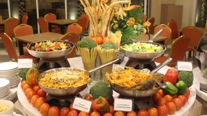 A buffet with various dishes labeled, including pasta, salad, and a mix of vegetables.