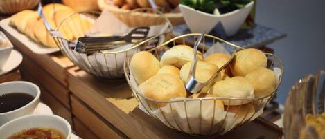 A buffet table with various food items including bread rolls and bowls of soup.
