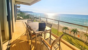 Un balcón con mesa y sillas, con vista a una playa y al océano.