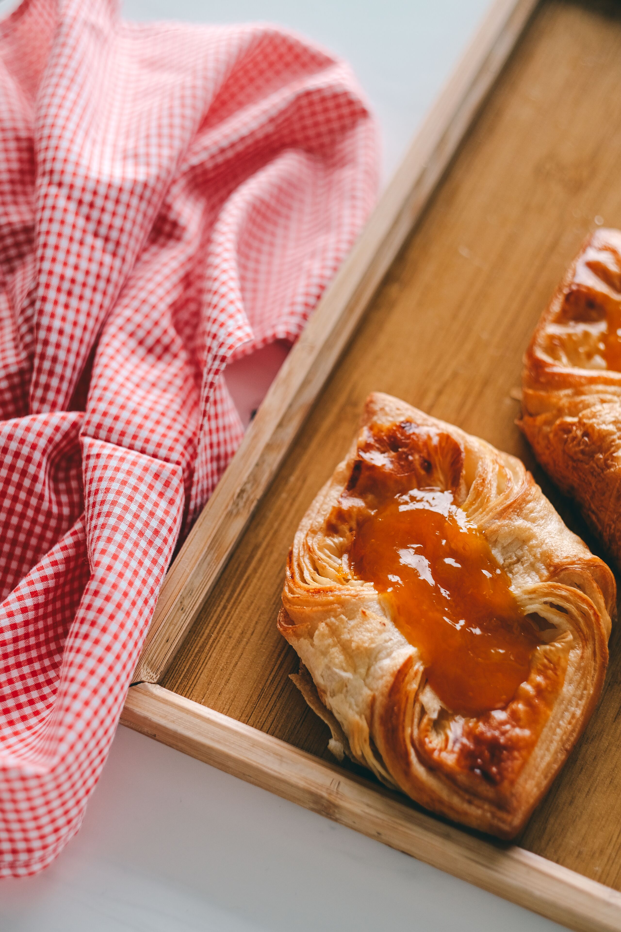 A wooden tray with pastries on a checkered cloth.