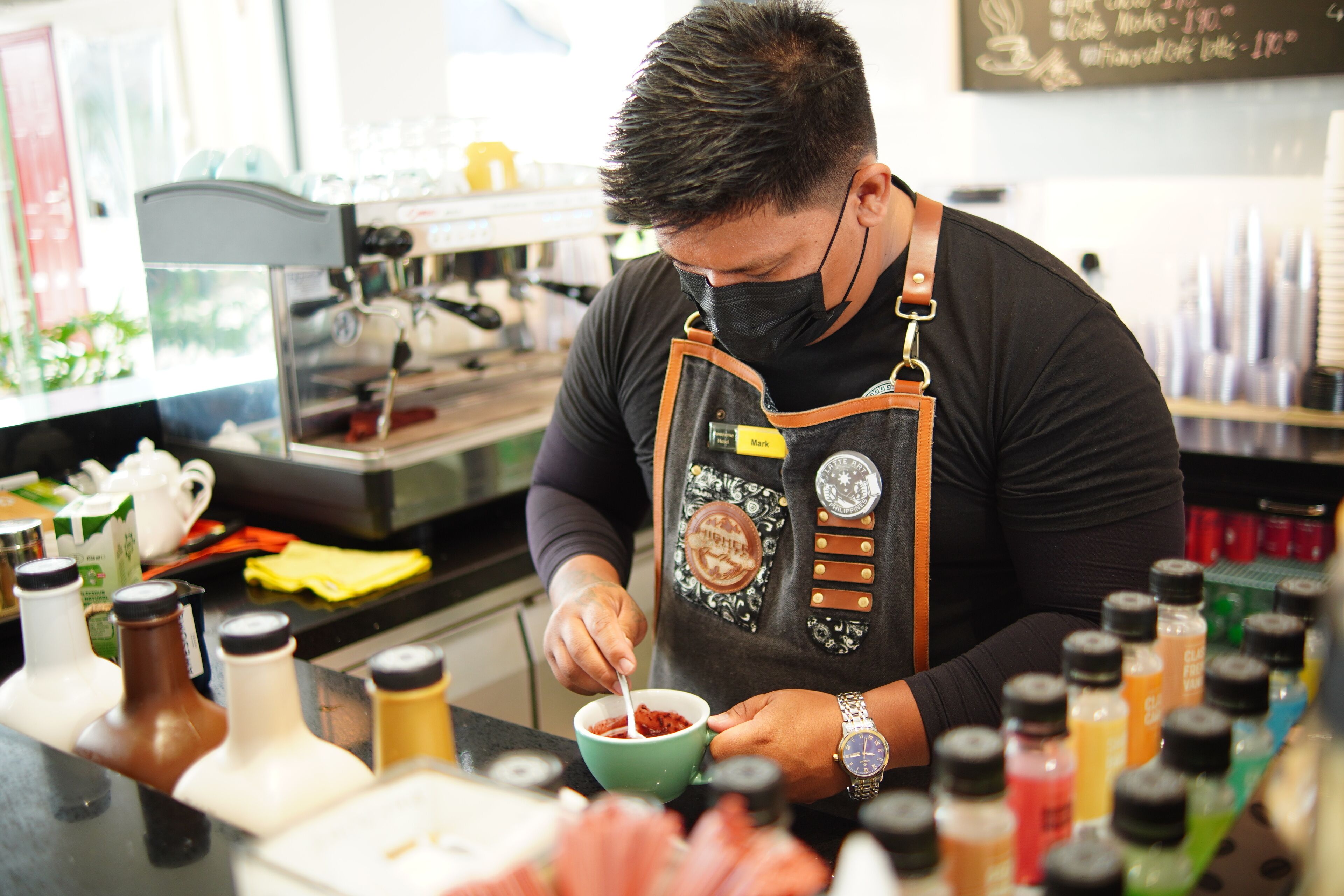 A person preparing food at a counter with various condiments and ingredients.