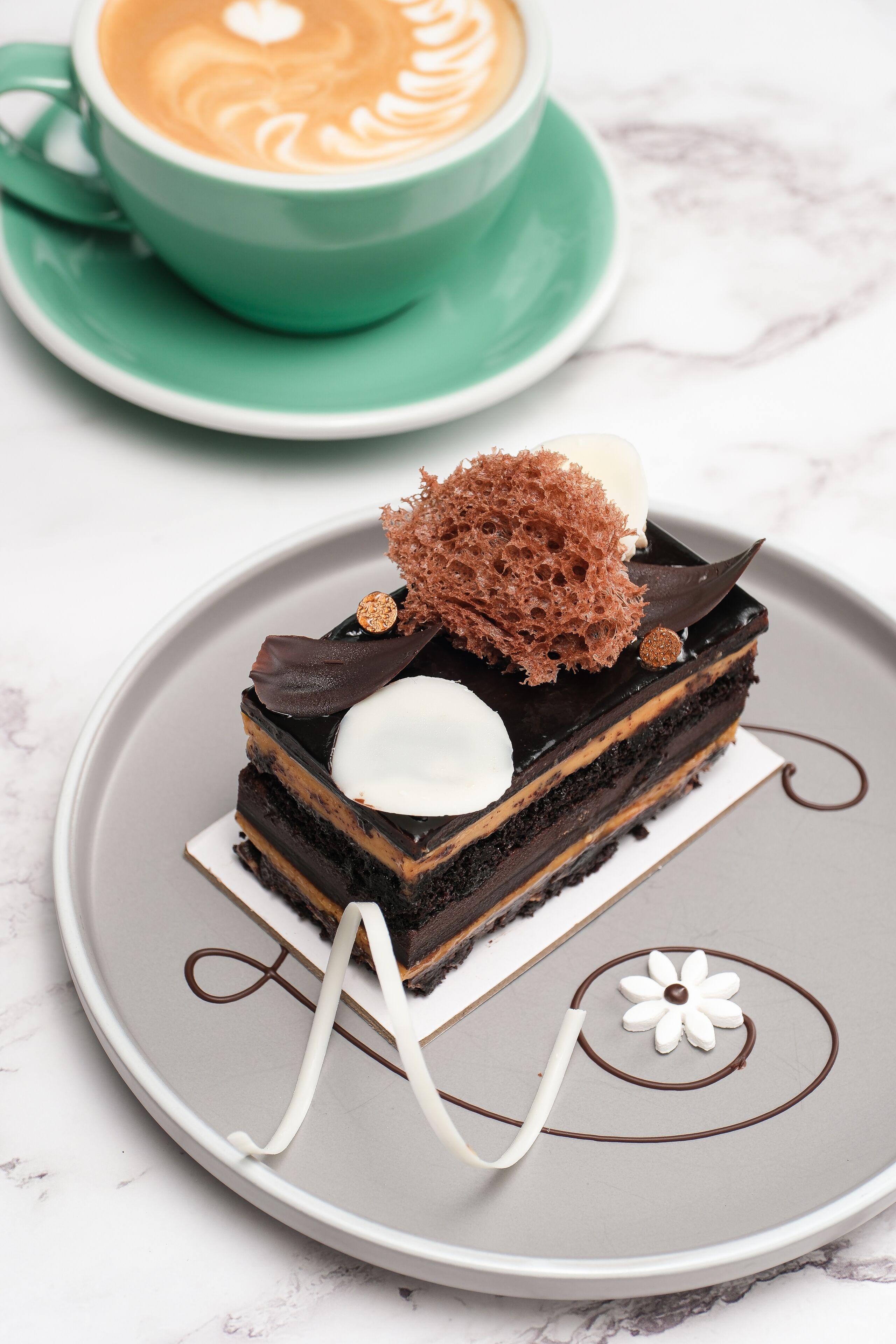 A slice of layered chocolate cake with whipped cream and chocolate decorations on a plate.