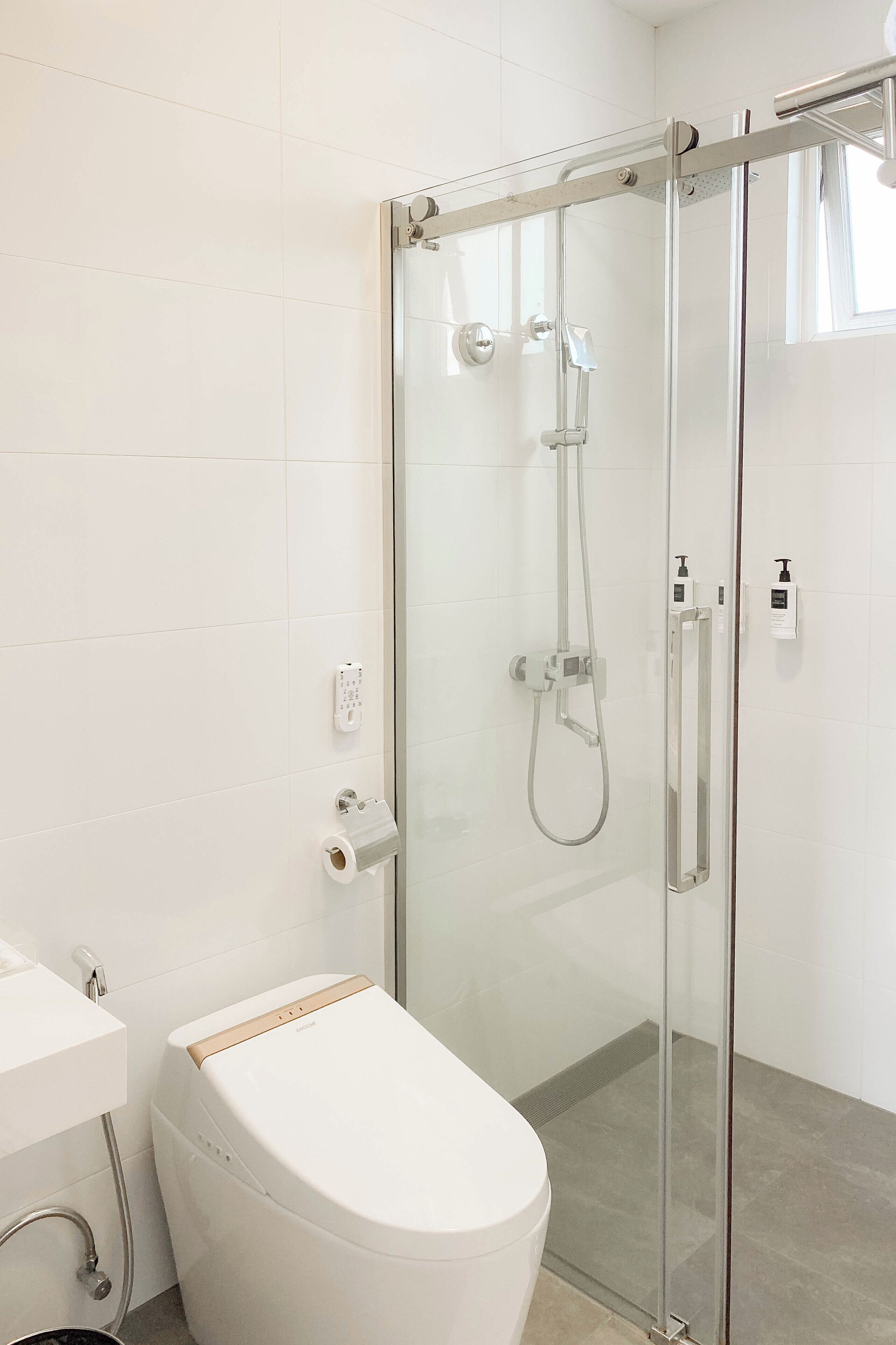 Een moderne badkamer met een douchecabine van glas, een toilet en een wastafel.