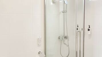 Een moderne badkamer met een douchecabine van glas, een toilet en een wastafel.