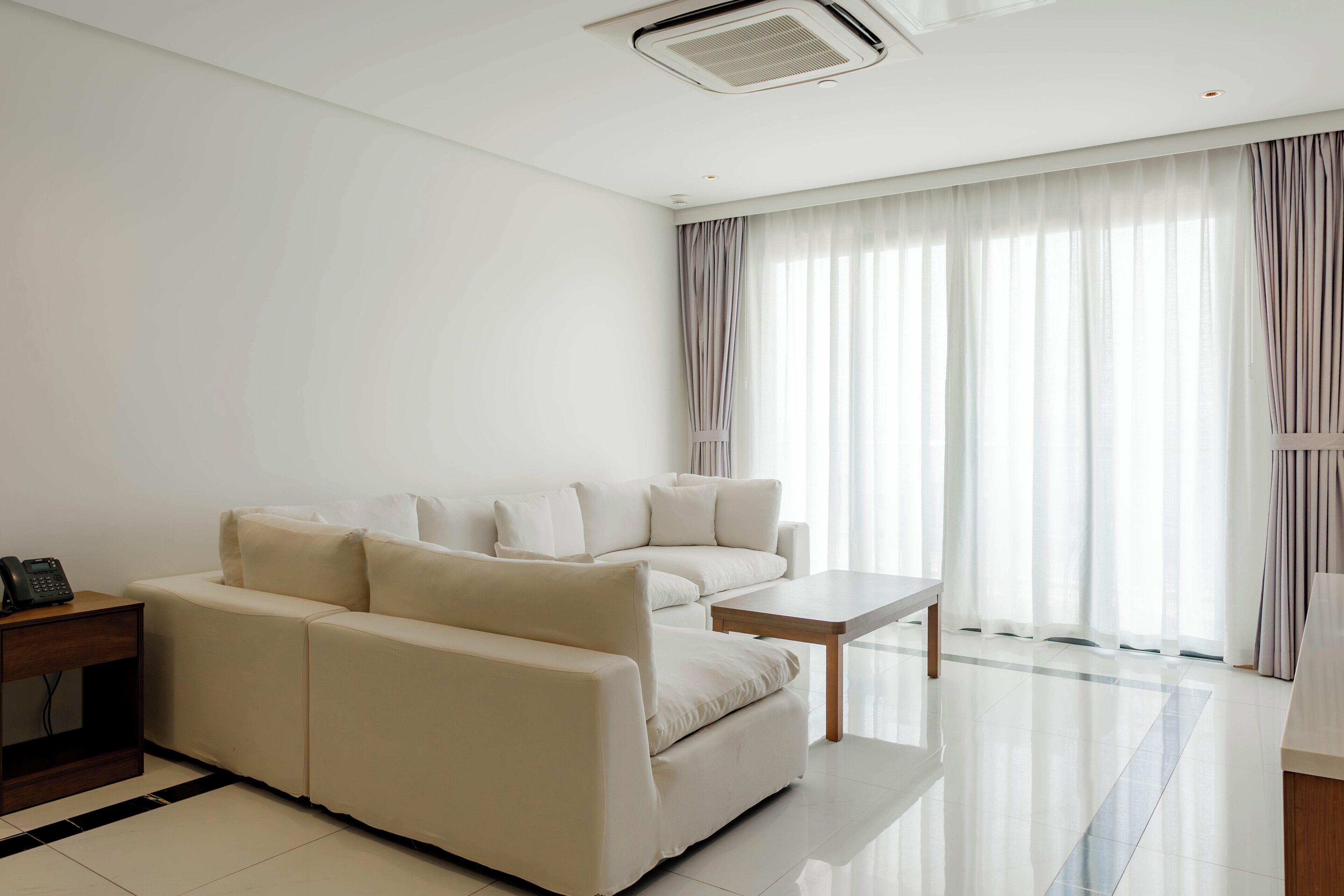 A modern living room with a sofa, a small table, and a telephone on a side table.