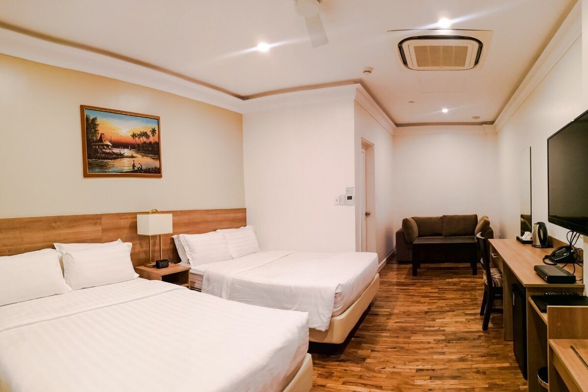 Een hotelkamer met twee bedden, een bureau, een televisie en een schilderij aan de muur.