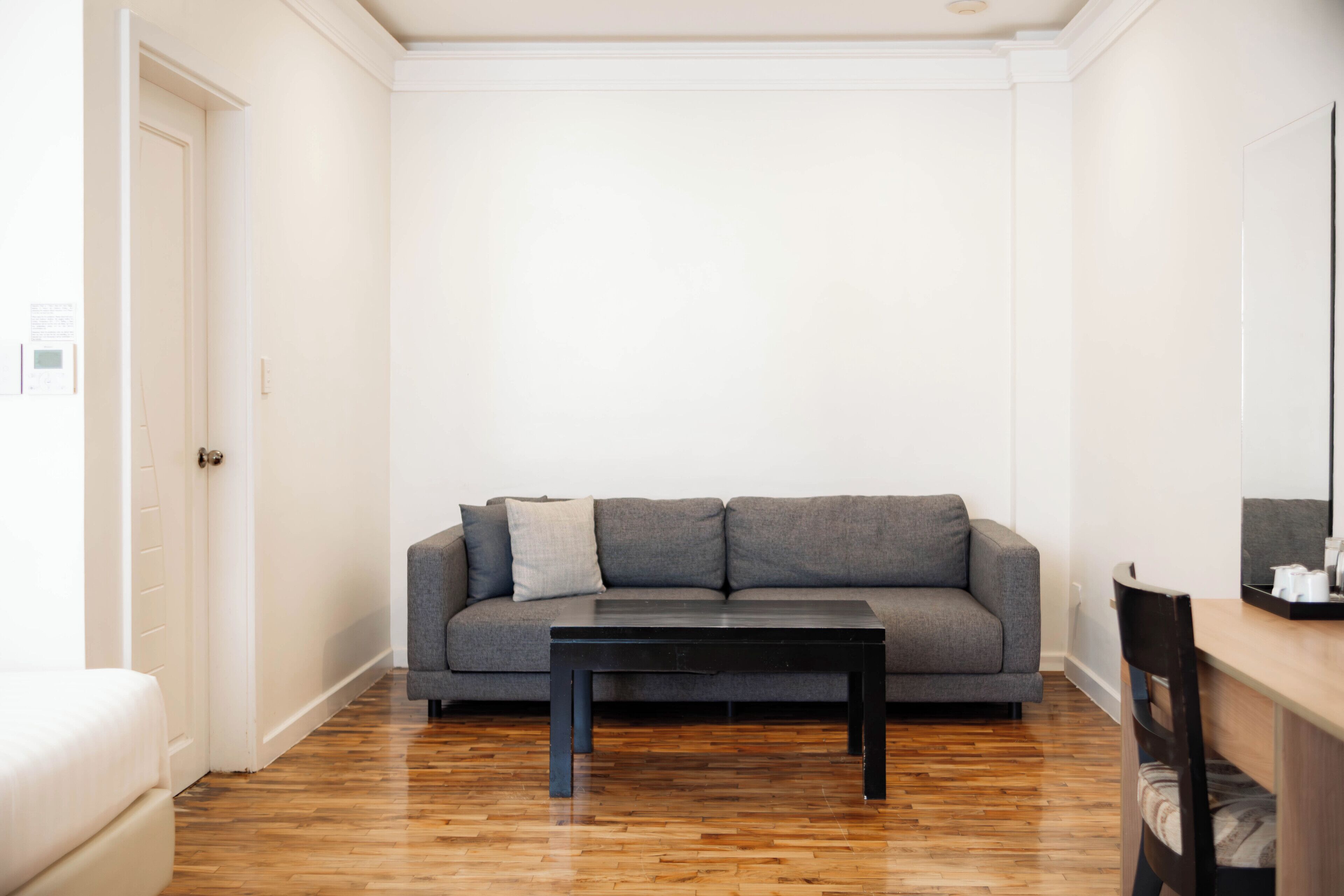 A room with a grey sofa, a black table, and a wooden floor.