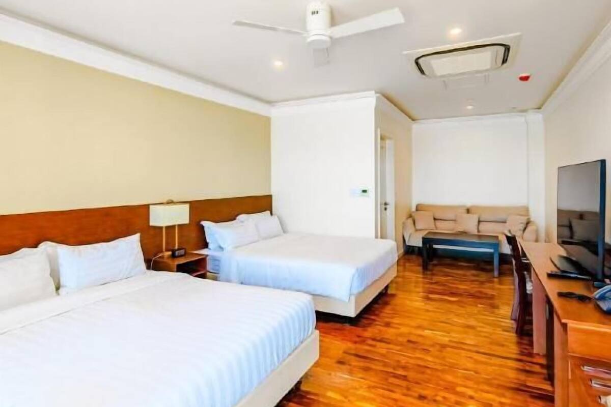Une chambre d’hôtel avec deux lits, un ventilateur de plafond, une télévision et un plancher en bois.