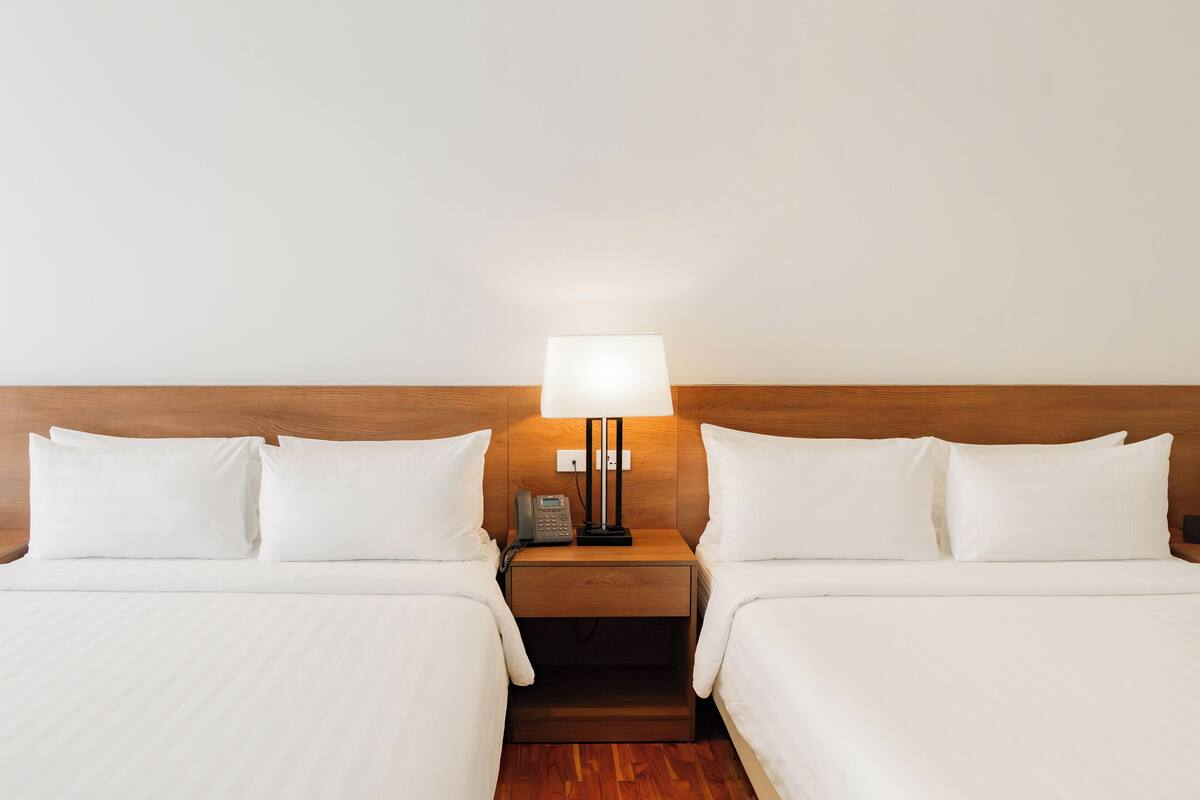 Une chambre d’hôtel avec deux lits, une table de chevet avec une lampe et un téléphone.
