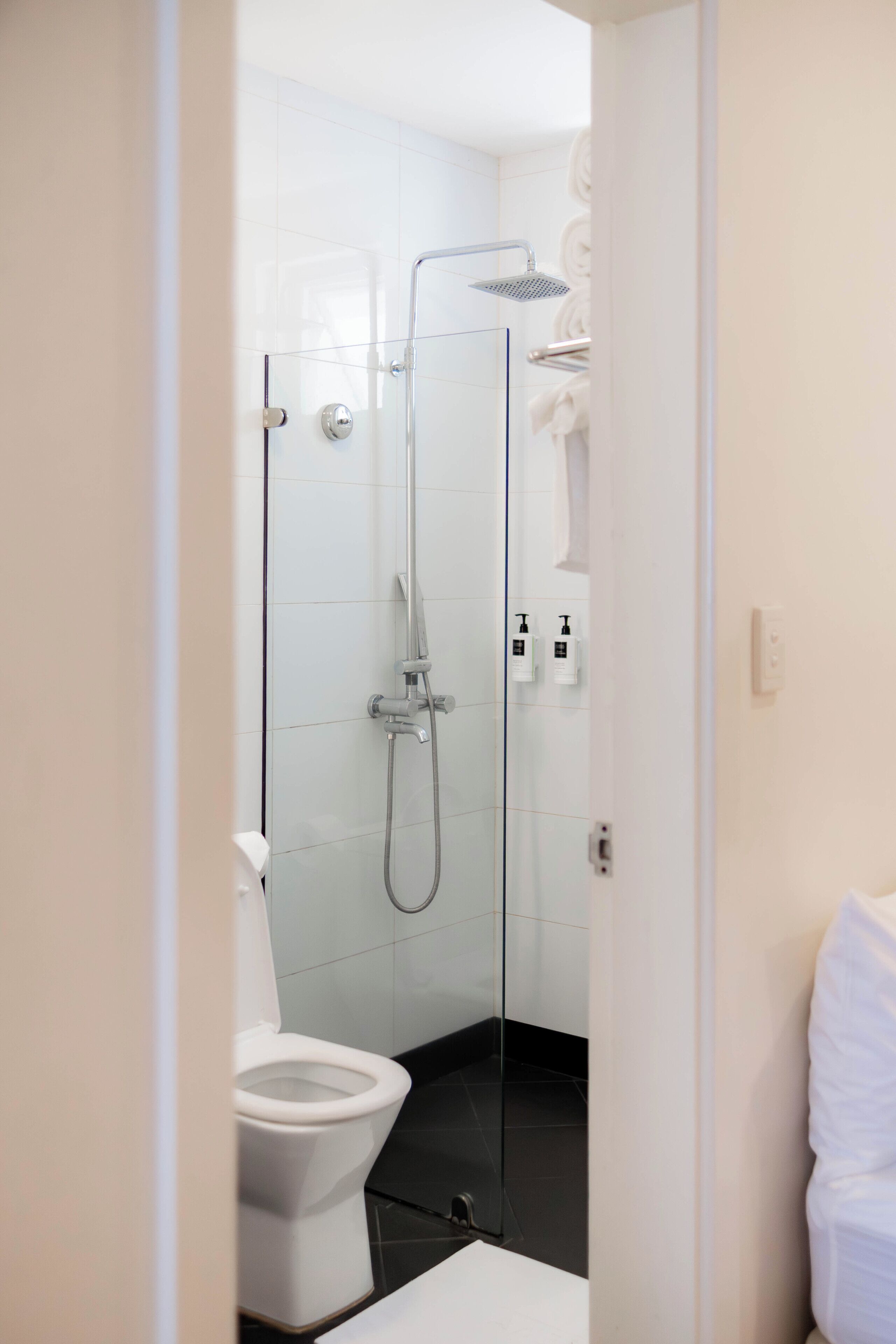 Een moderne badkamer met een douchekabinet van glas, een wit toilet en een witte wastafel.