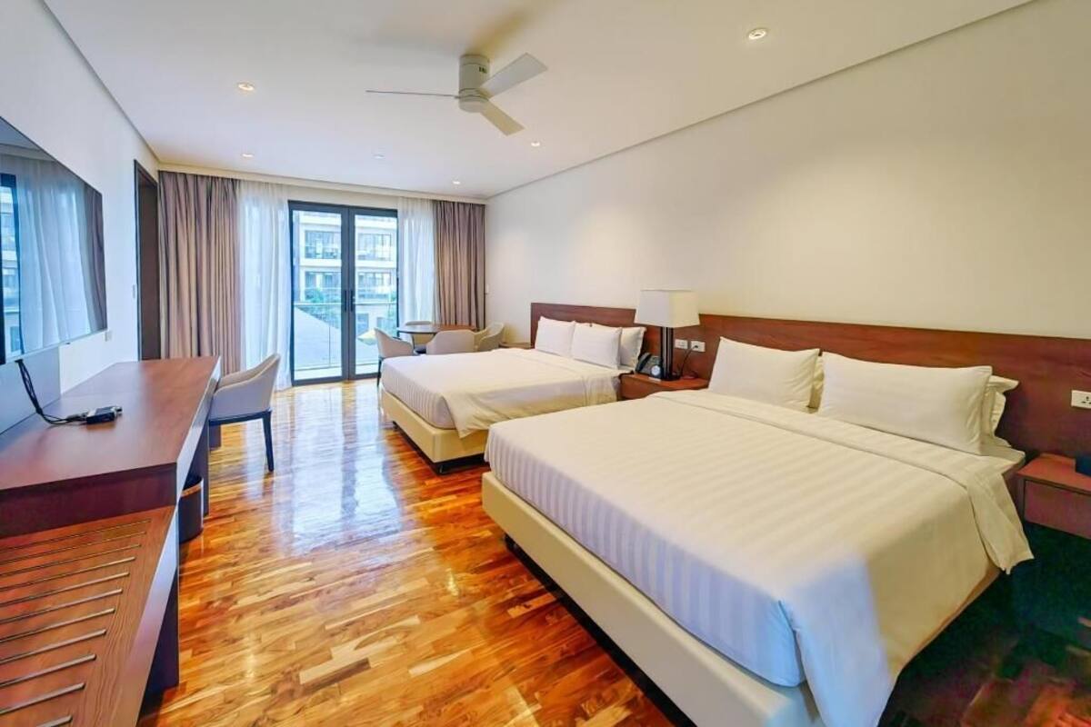 Une chambre d’hôtel avec deux lits, un bureau, une chaise et une vue sur la ville.