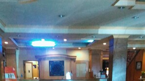 A spacious lobby with a reception desk, a large framed artwork on the wall, and a red carpet leading to the entrance. - Hotel Buana Lestari (Balikpapan)
