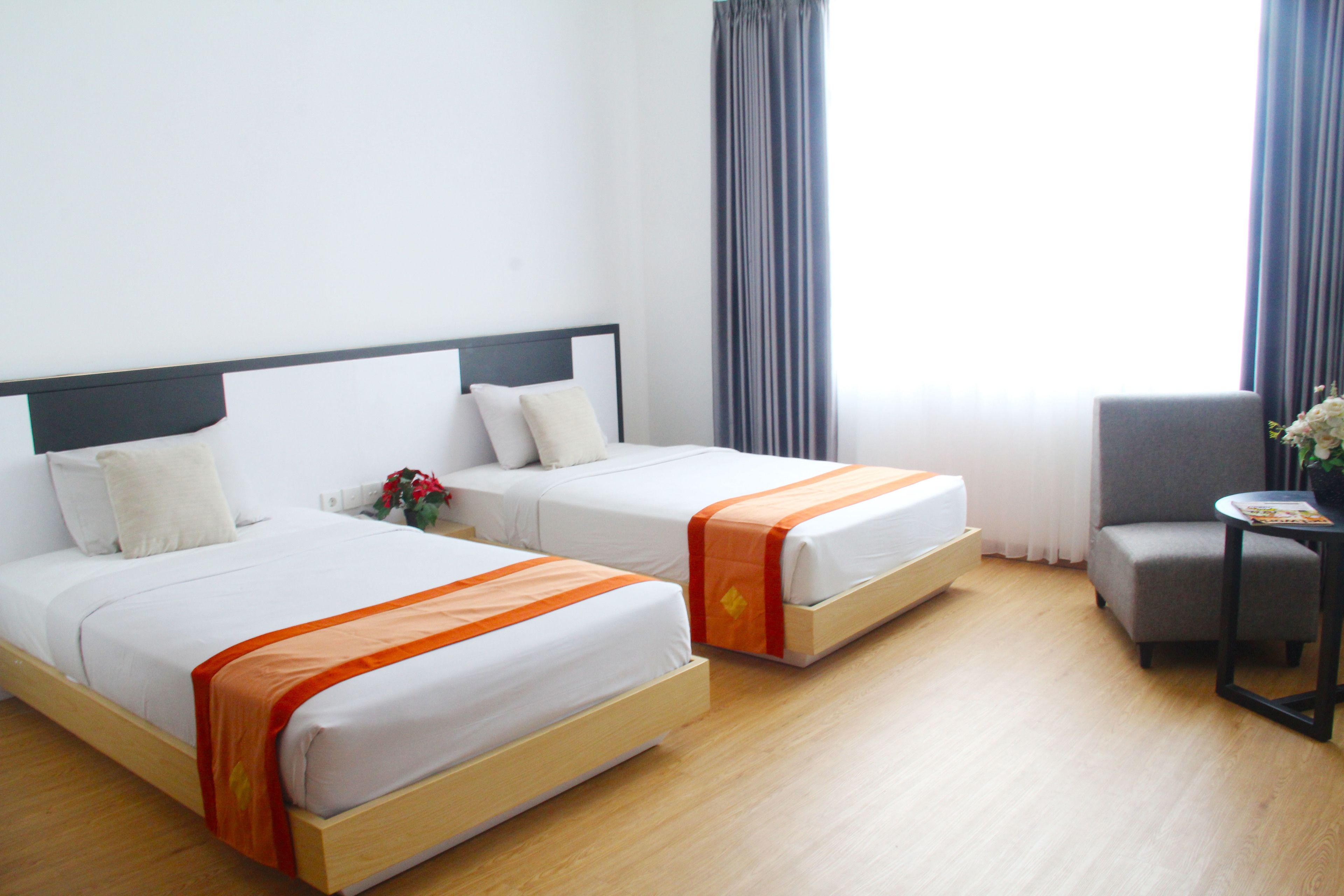 A hotel room with two beds, a small table, and a chair.