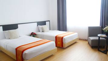 A hotel room with two beds, a small table, and a chair.