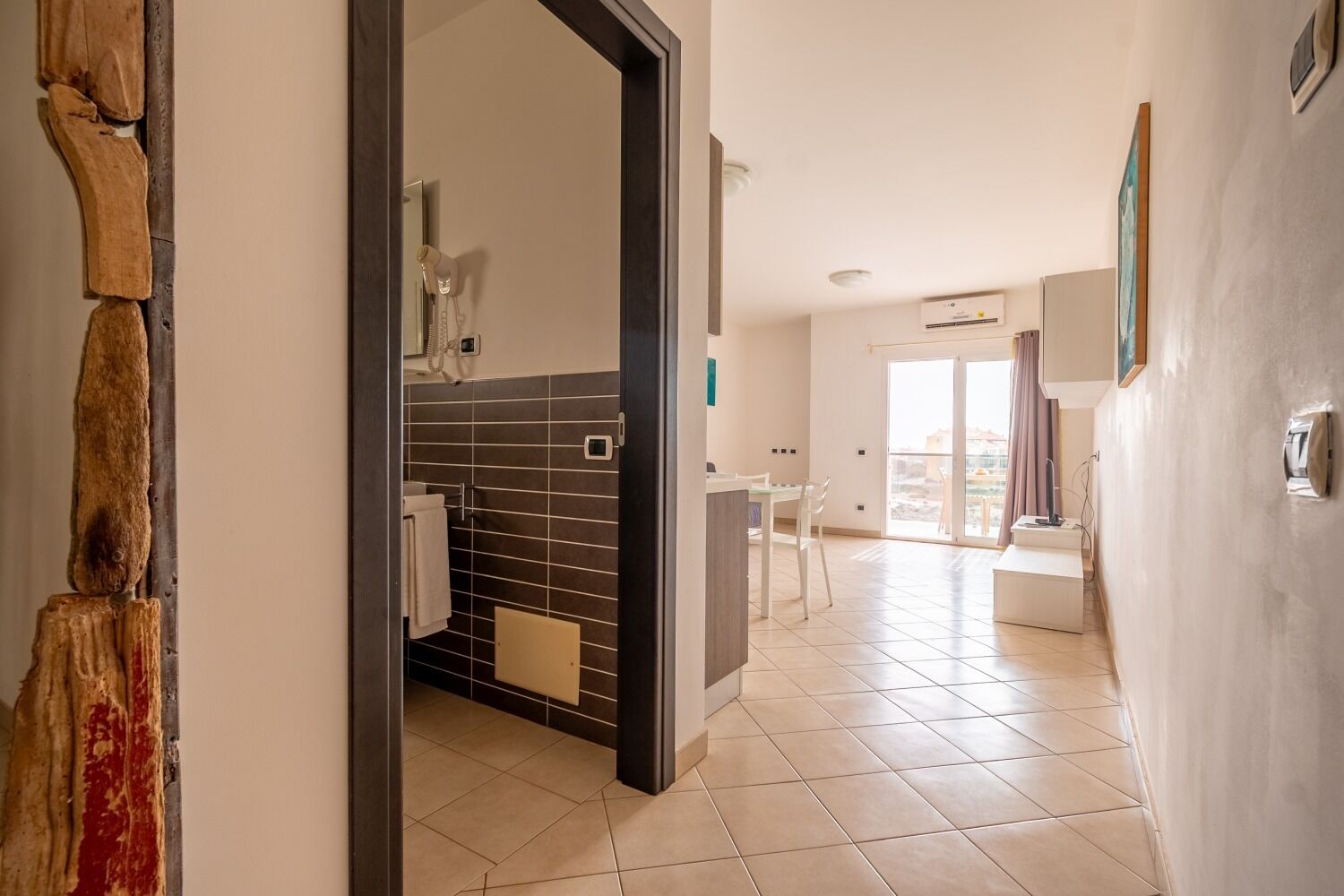 Una habitación de hotel moderna con baño, zona de comedor y balcón.