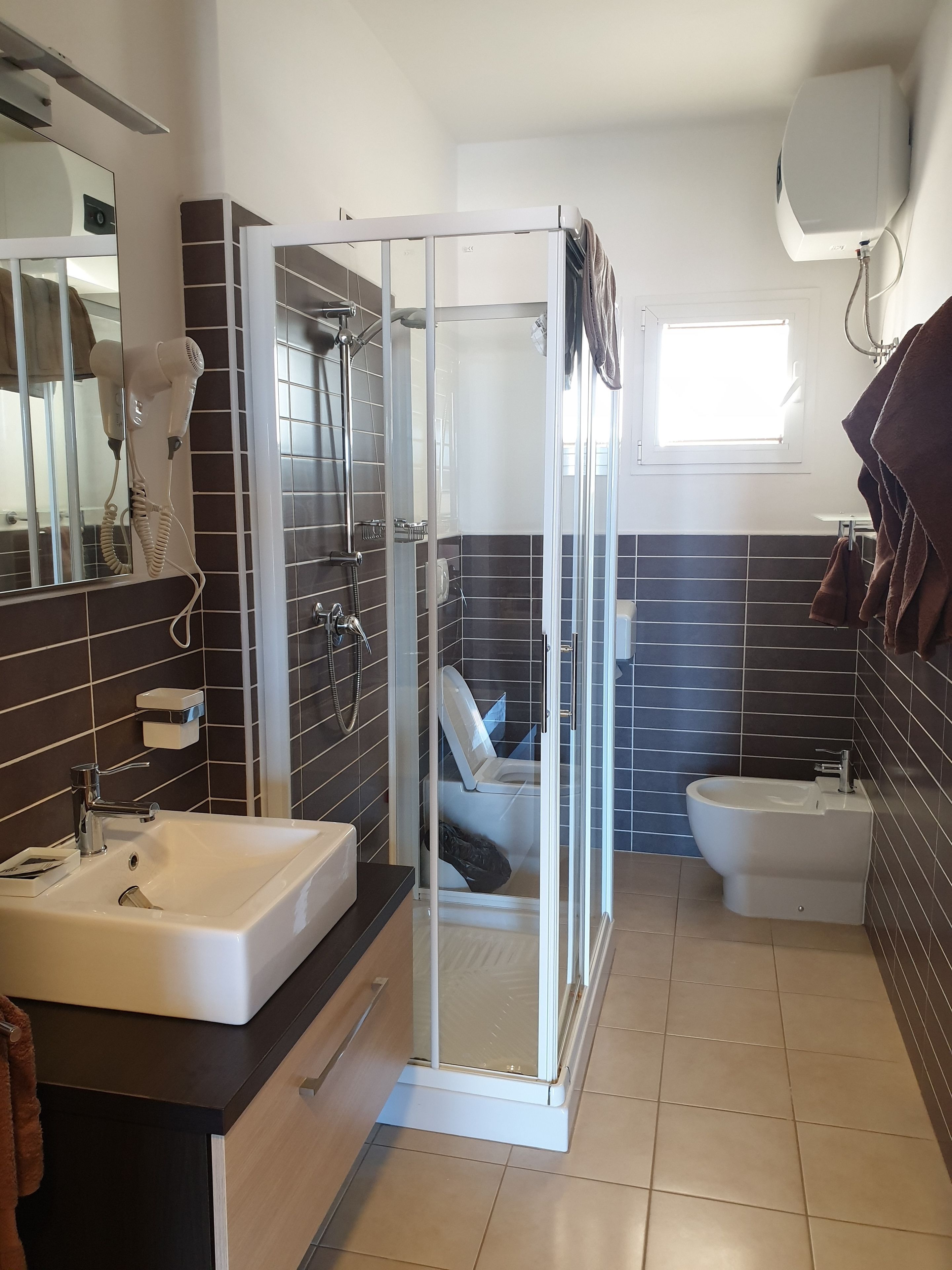 A modern bathroom with a glass-enclosed shower, a white sink, and a bidet.