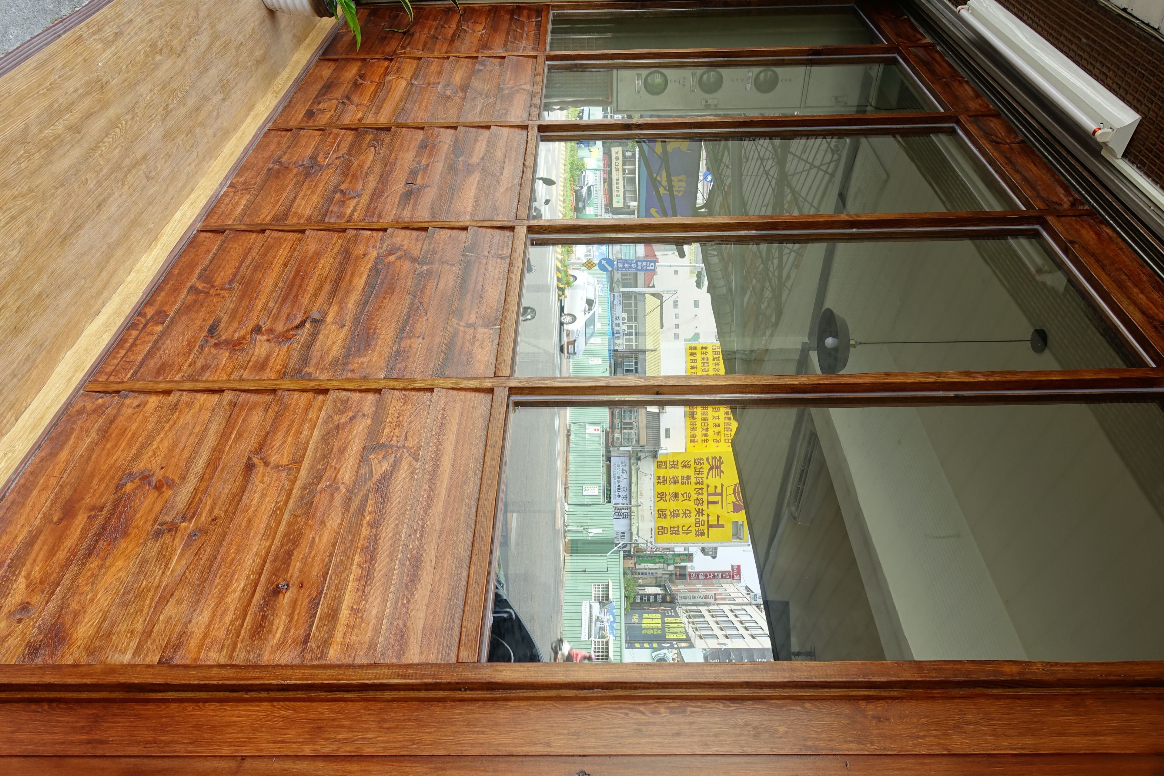 Suelo de madera con un amplio ventanal que refleja un paisaje urbano.