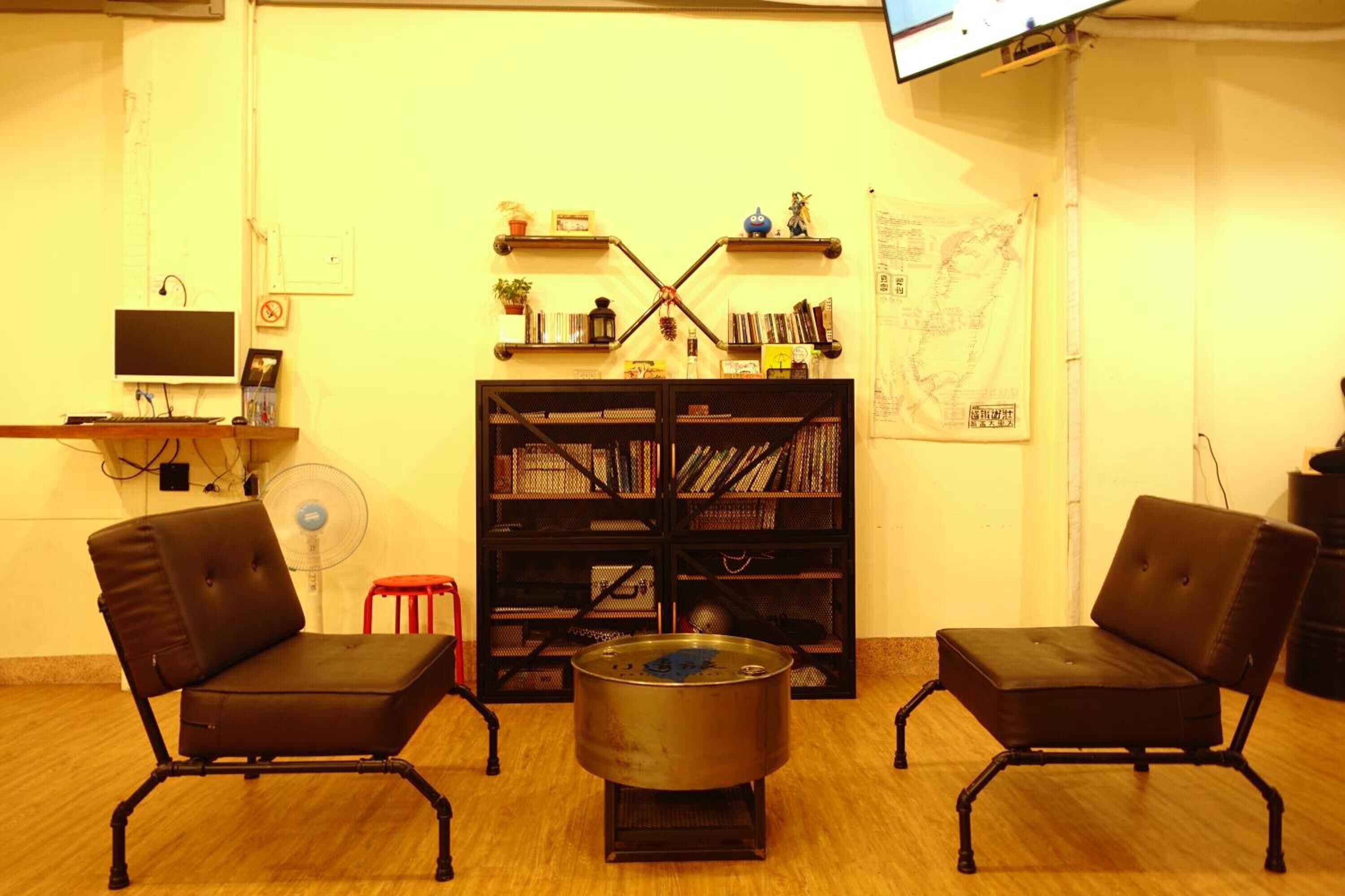 A room with two black leather chairs, a small table, a bookshelf, and a map on the wall.