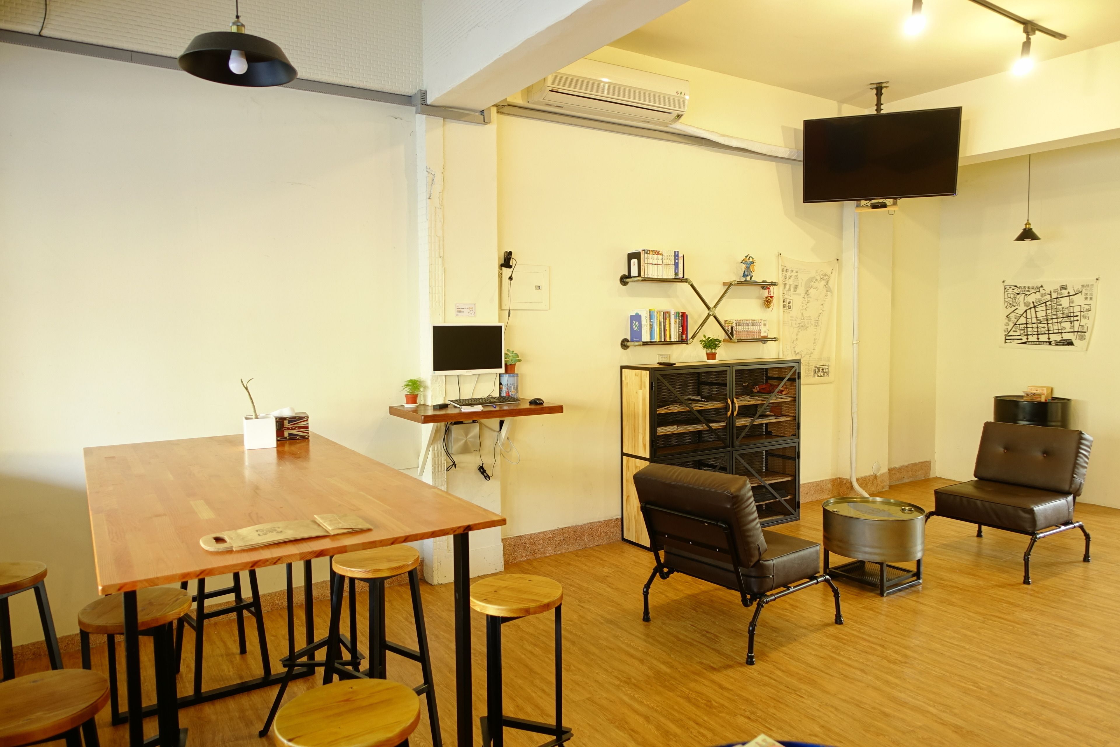 A cozy room with a wooden table, bar stools, a sofa, and a TV mounted on the wall.