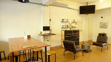 A cozy room with a wooden table, bar stools, a sofa, and a TV mounted on the wall.