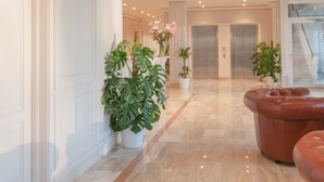 Un hall d’entrée spacieux, doté d’un sol en marbre, de plantes en pot et d’un canapé en cuir.