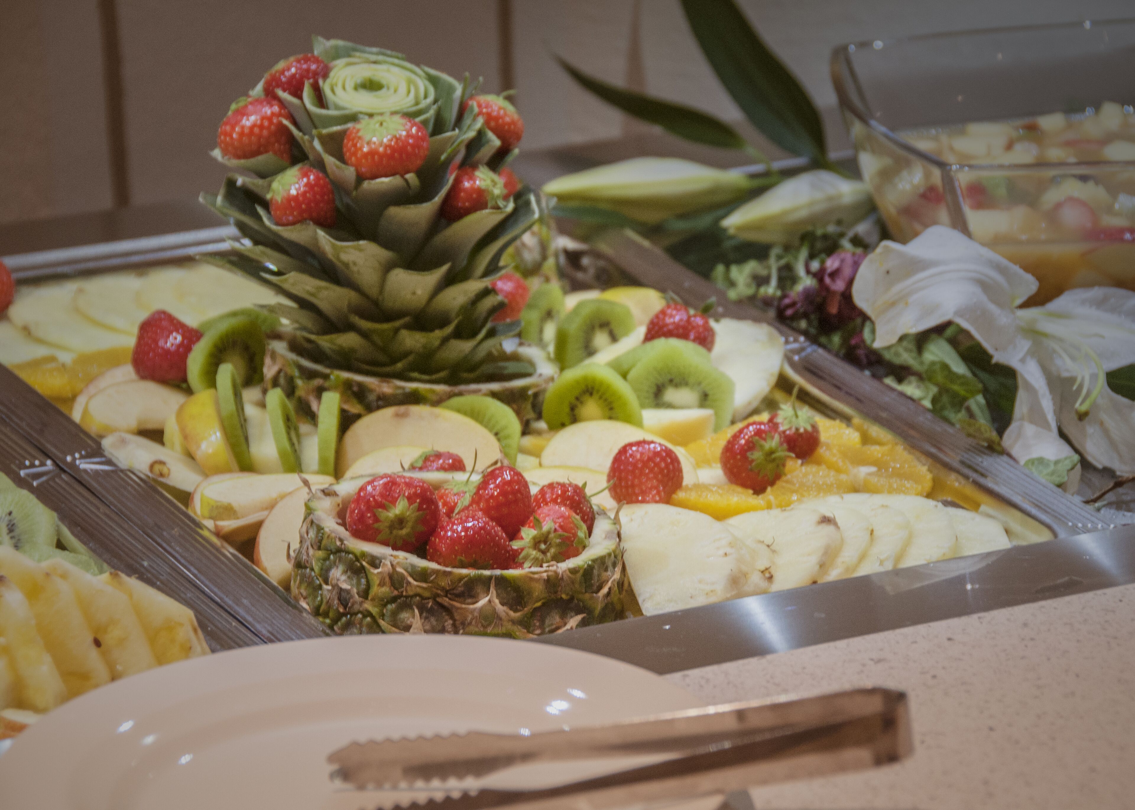 A buffet with various fruits and vegetables, including strawberries, kiwi, and pineapple.