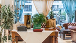 Une table recouverte d’une nappe blanche, un chandelier, une bouteille de vin, un livre vert et un ananas.
