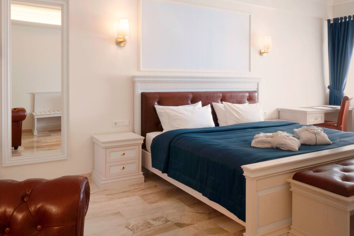 A hotel room with a large bed, a nightstand, a chair, and a desk.