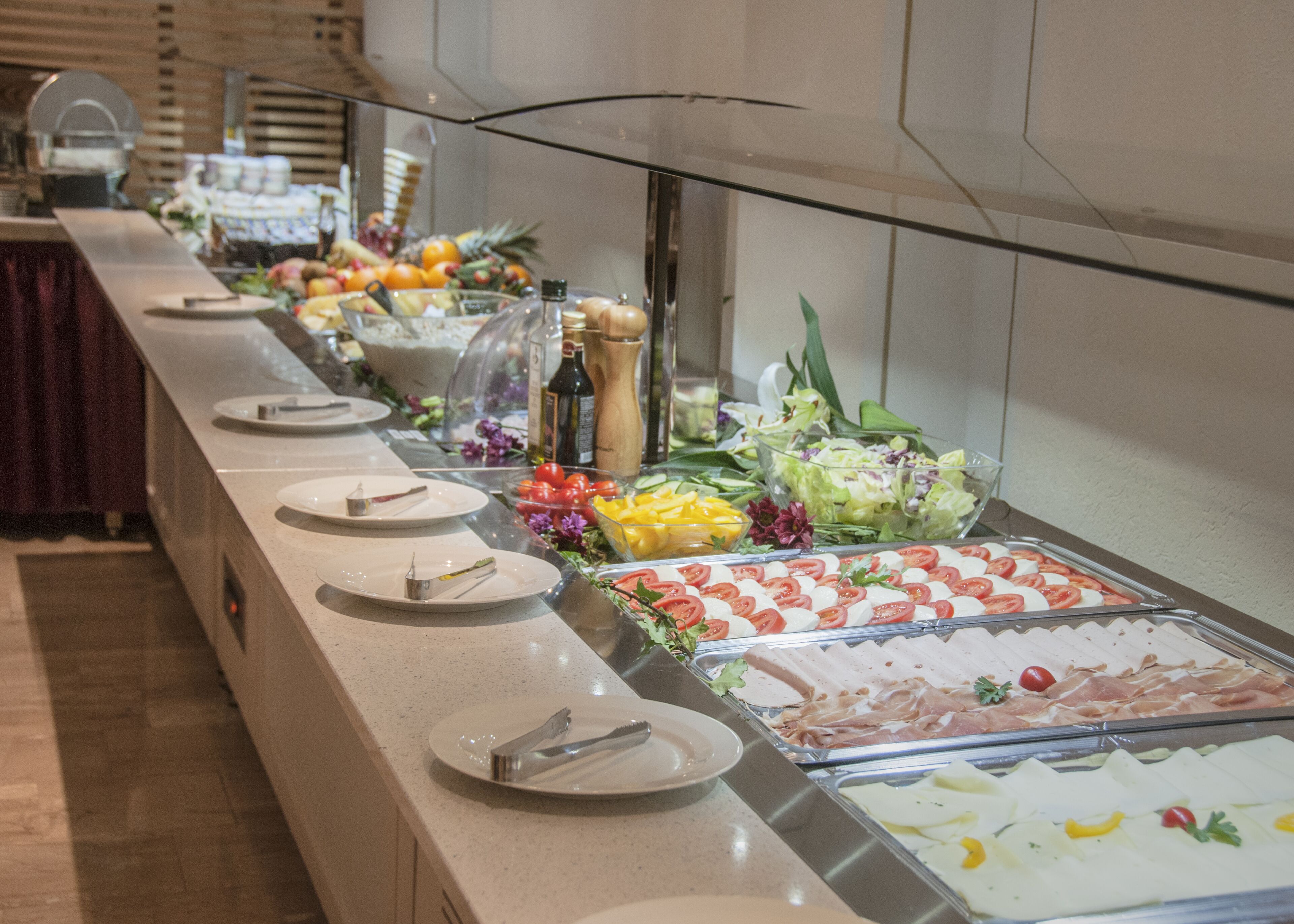 A buffet with various food items including salads, fruits, and meats.