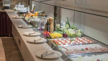 A buffet with various food items including salads, fruits, and meats.