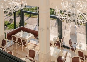 A restaurant with outdoor seating, white tables, and chairs, and a chandelier. - Grand Hotel Palladium Munich (Munich)