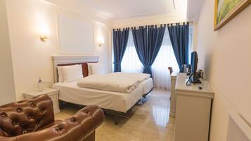 Una habitació d'hotel amb un llit, una taula de treball, una cadira i una nitzeta.