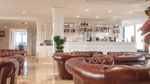Un espace bar avec des canapés en cuir, un comptoir de bar orné de bouteilles et de verres, et une grande plante en pot.