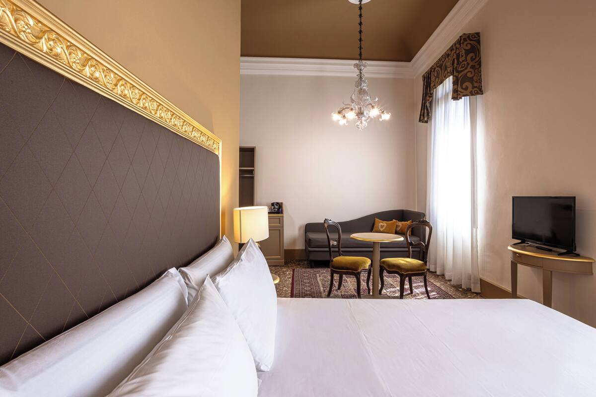 Ein Hotelzimmer mit einem großen Bett, einer Couch, einem kleinen Tisch und einem Fernseher.