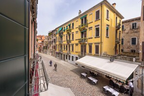 A cobblestone street with yellow buildings, outdoor seating, and a café. - Antico Portego (Venice)