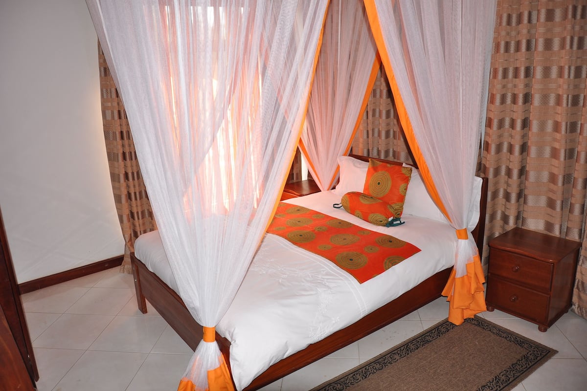 A bed with a canopy, a bedside table, and a patterned bedspread.