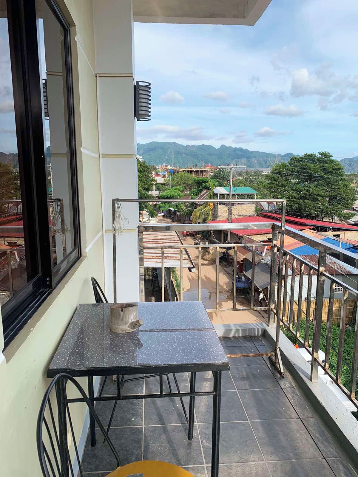 A balcony with a table and chairs, overlooking a construction site and a mountainous landscape.