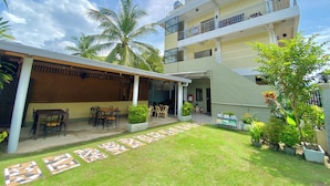 A two-story building with a covered patio area, outdoor seating, and a small garden with potted plants. - Coron Vista Lodge (Coron)