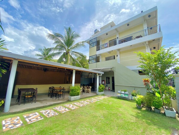 A two-story building with a covered patio area, outdoor seating, and a small garden with potted plants. - Coron Vista Lodge (Coron)