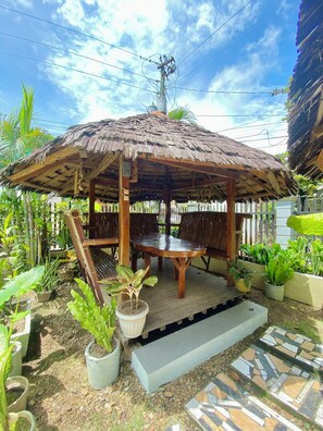A wooden gazebo with a thatched roof, surrounded by potted plants and a tiled patio area. - Coron Vista Lodge (Coron)