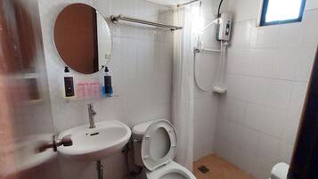 A small bathroom with a sink, toilet, and shower.