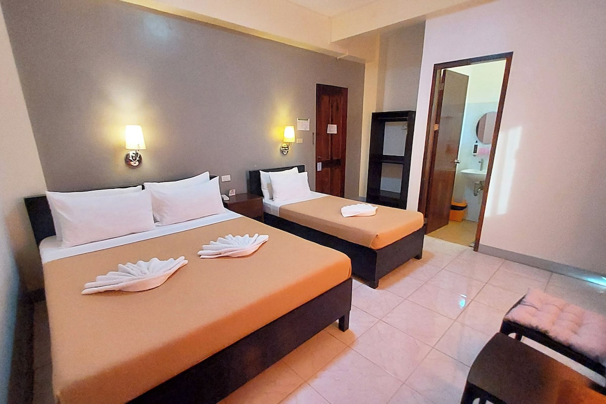 A hotel room with two beds, a small table, and a chair.