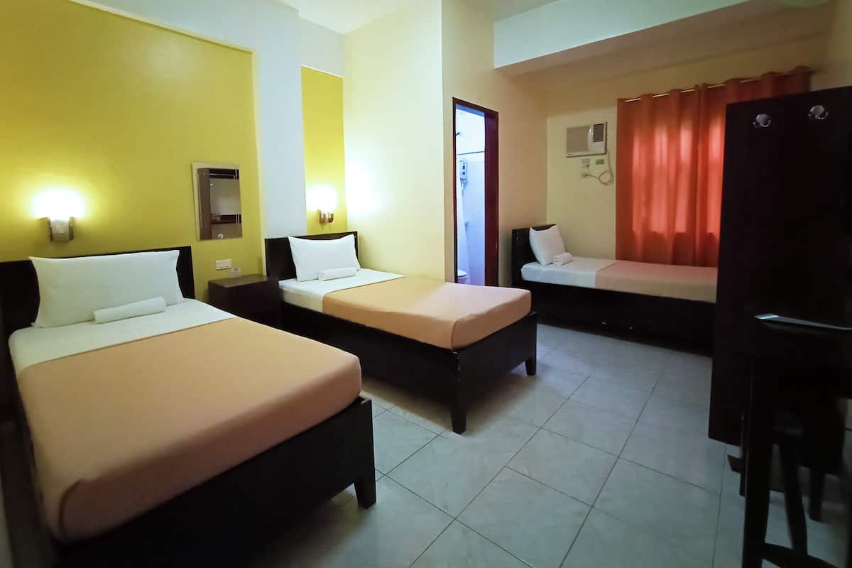 A hotel room with two beds, a desk, and a bathroom visible through an open door.