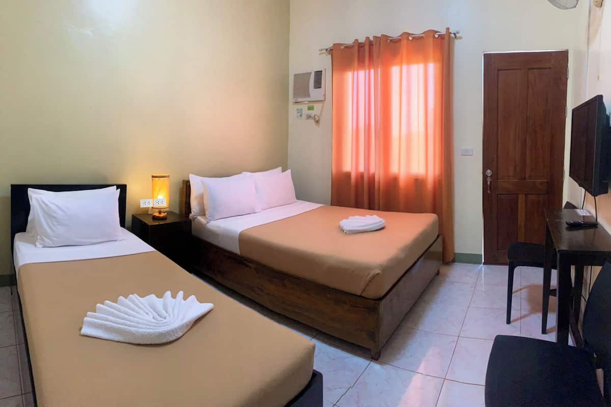 A hotel room with two beds, a desk, a chair, a television, and a window with curtains.