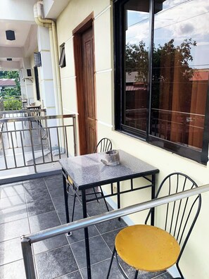 A balcony with a table and chairs, a window, and a door. - Coron Vista Lodge (Coron)