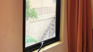 A window with a black frame and a view of a building with a bamboo wall and a staircase. - Coron Vista Lodge (Coron)