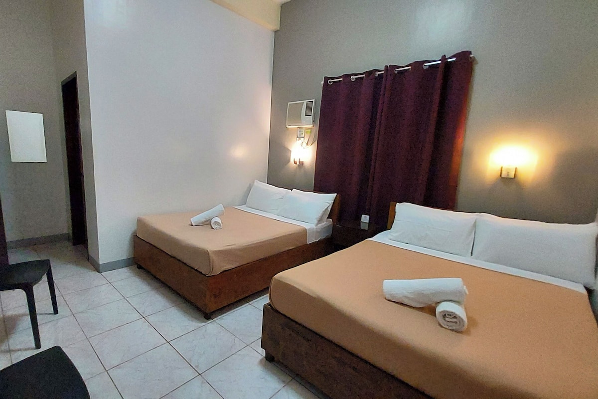 A hotel room with two beds, a desk, and a chair.