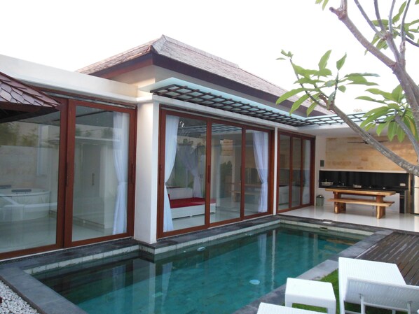 A modern house with a swimming pool, large glass windows, and a wooden deck.