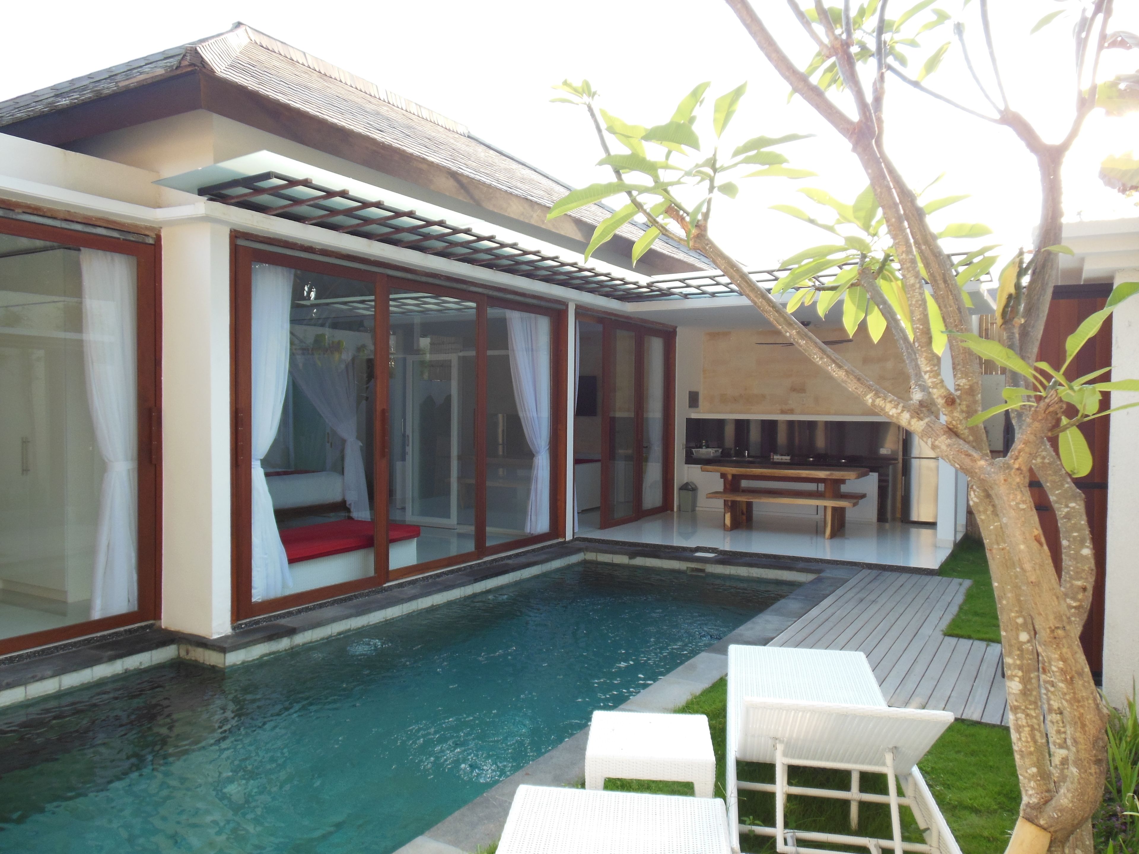 Una casa moderna con piscina, puertas de cristal y terraza de madera.