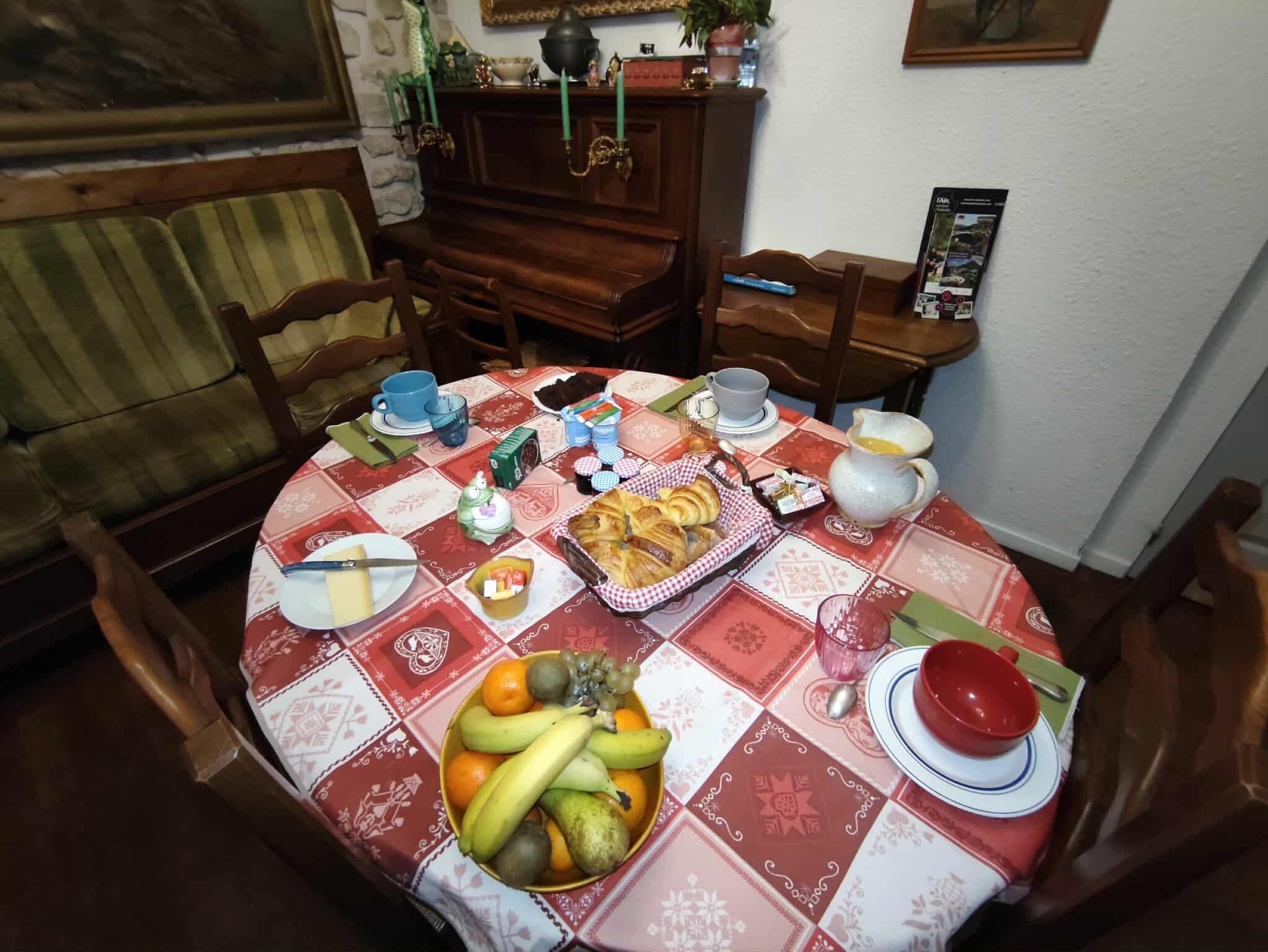 A dining table set with a variety of food items, including fruits, pastries, and a pitcher.
